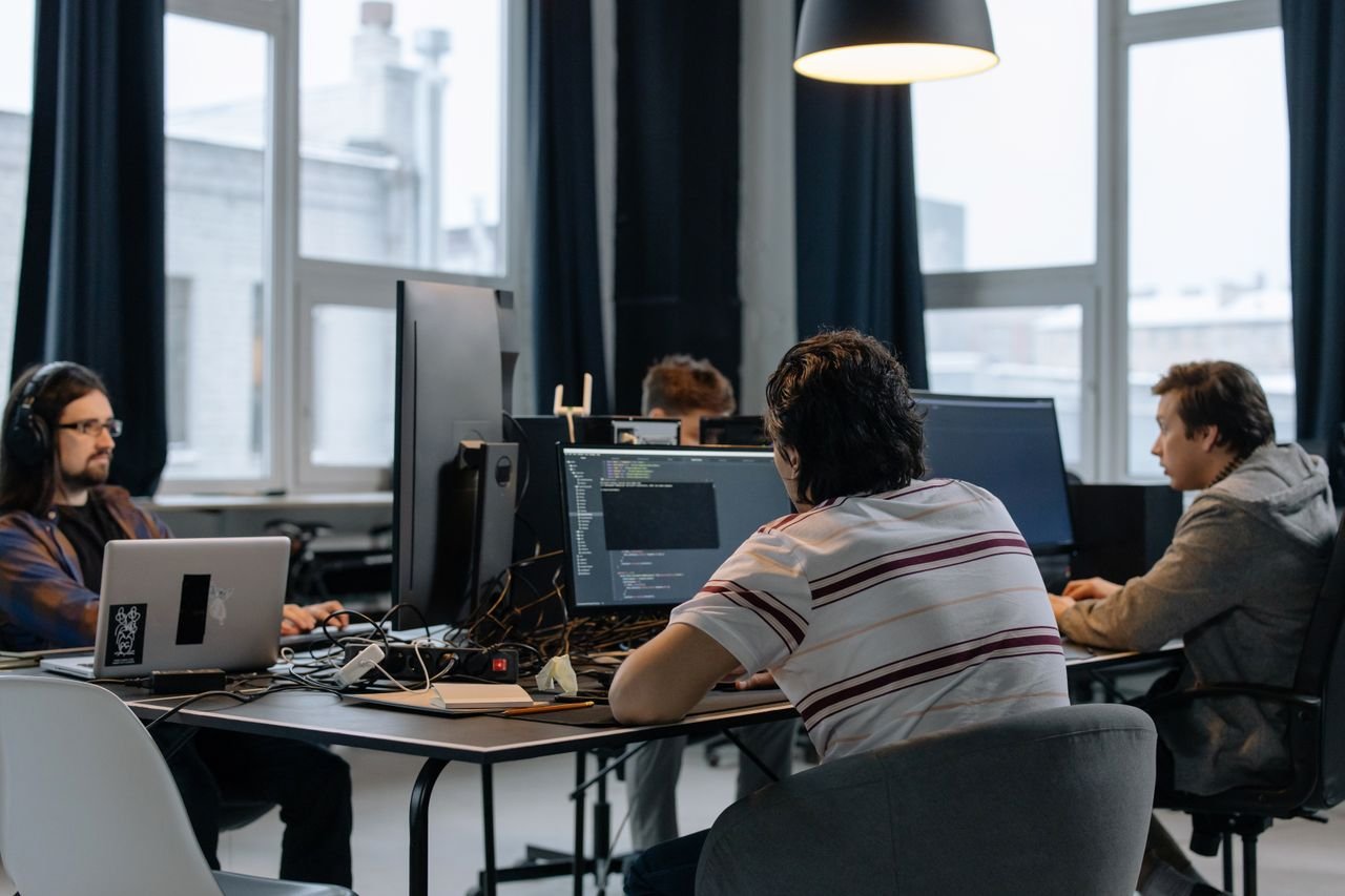Home Team of developers working together on computers in a modern tech office.